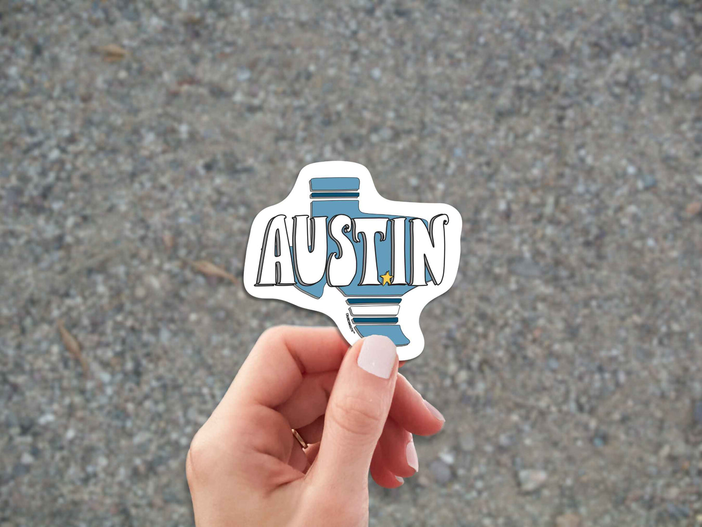 austin texas sticker, hand display, gravel road background