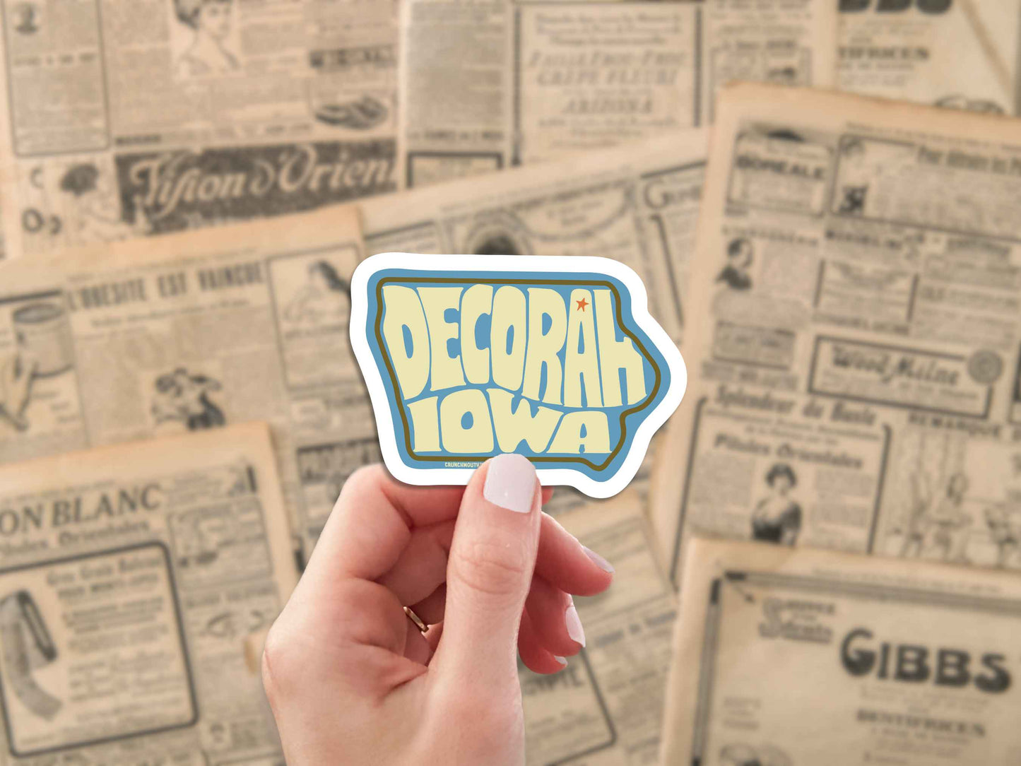 decorah iowa travel luggage sticker, hand display, antique newspaper ads background