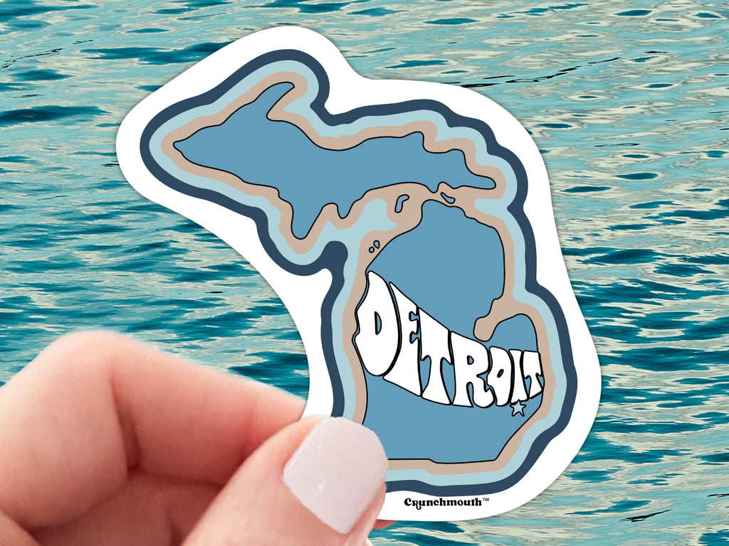 detroit michigan vinyl sticker, held in hand, blue ocean water background