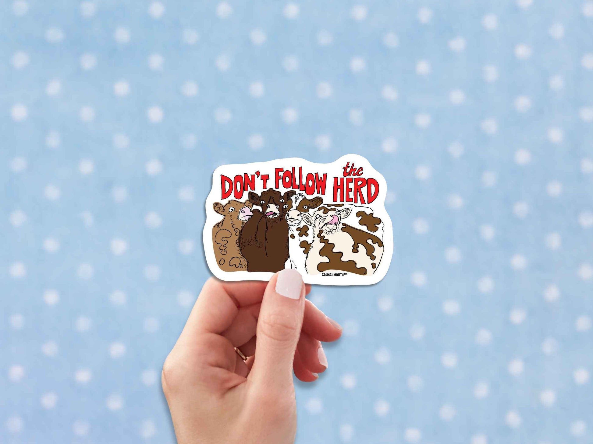 don't follow the herd sticker, hand display, polka dot fabric background