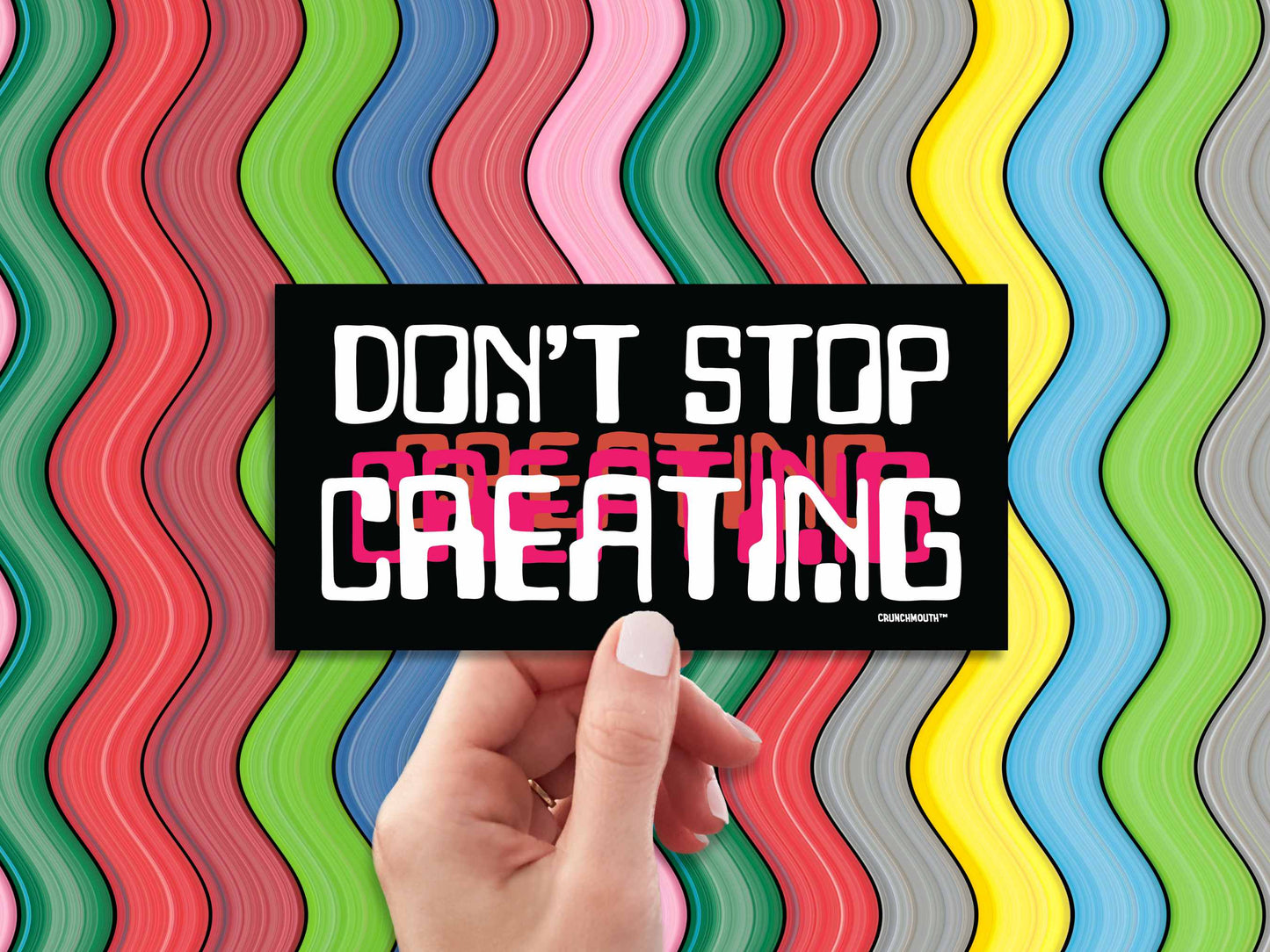 don't stop creating bumper sticker, hand display, colorful wavy stripes background