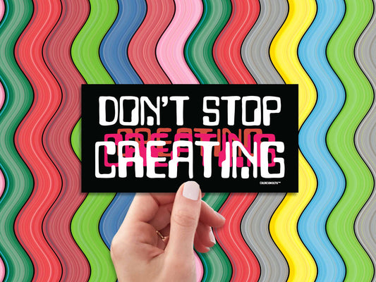 don't stop creating bumper sticker, hand display, colorful wavy stripes background
