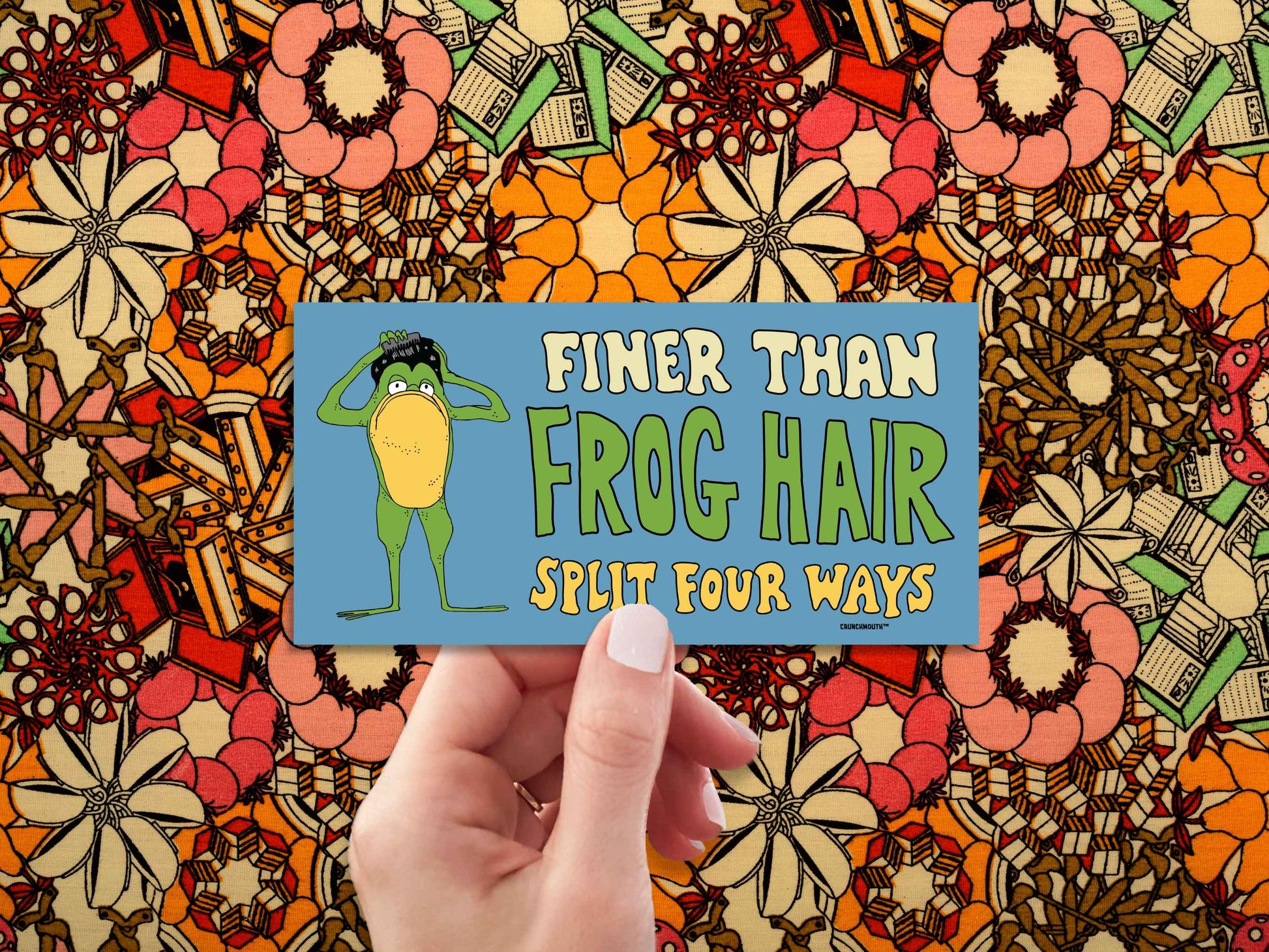 finer than frog hair split four ways bumper sticker, funny greaser frog combing hair, hand display, 1960s floral fabric pattern background
