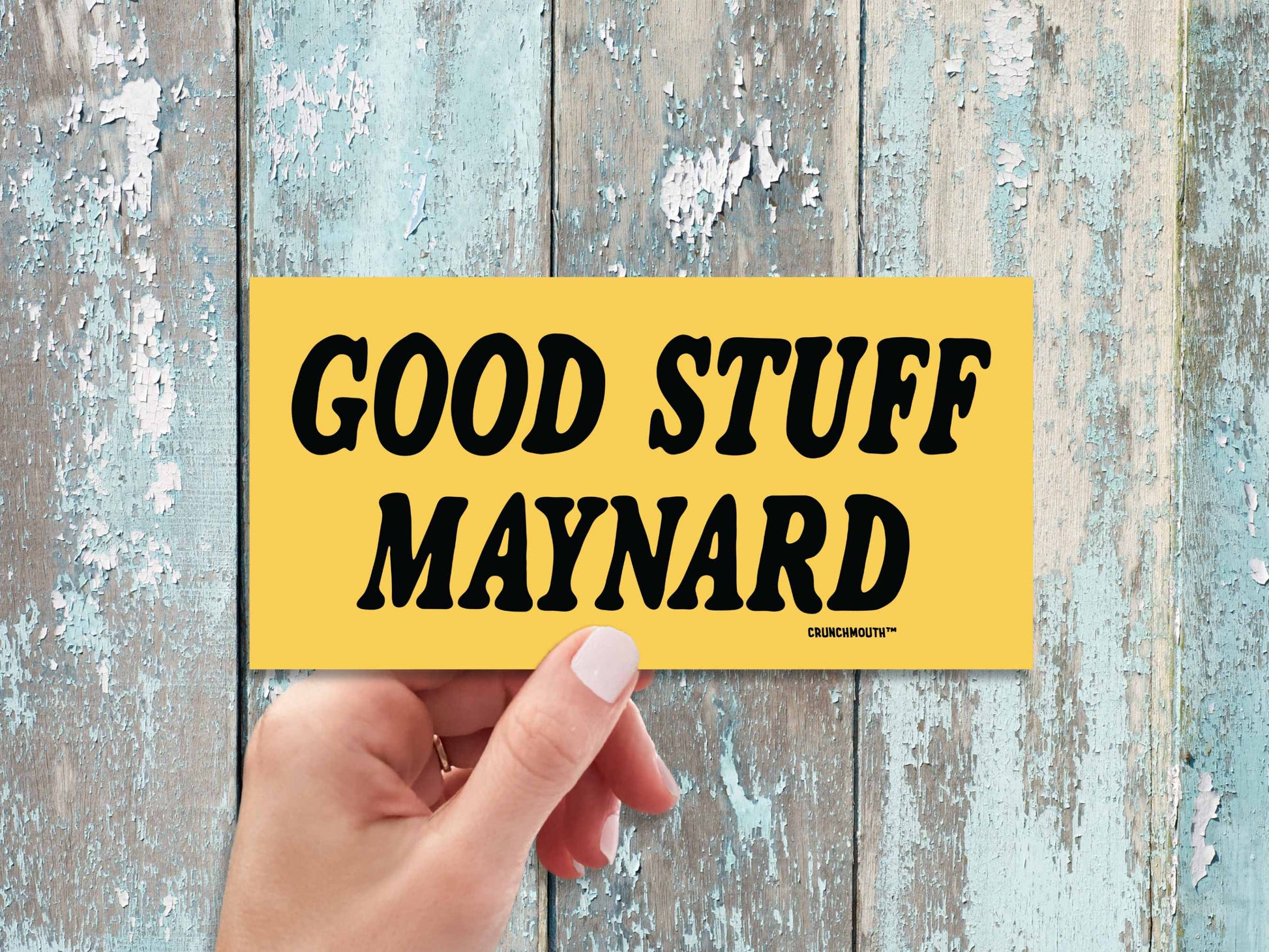good stuff maynard bumper sticker, hand display, weathered wood panel background