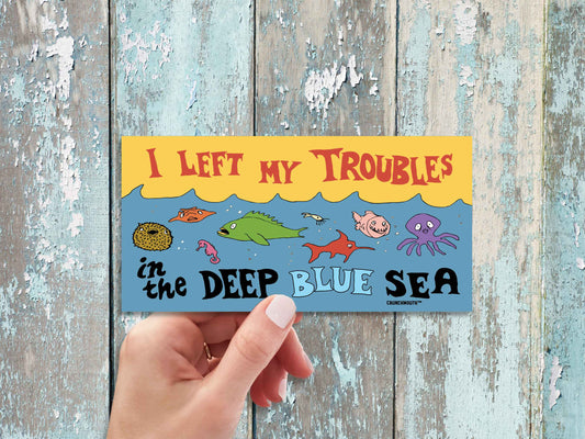 i left my troubles in the deep blue sea bumper sticker, hand display, wood panel background