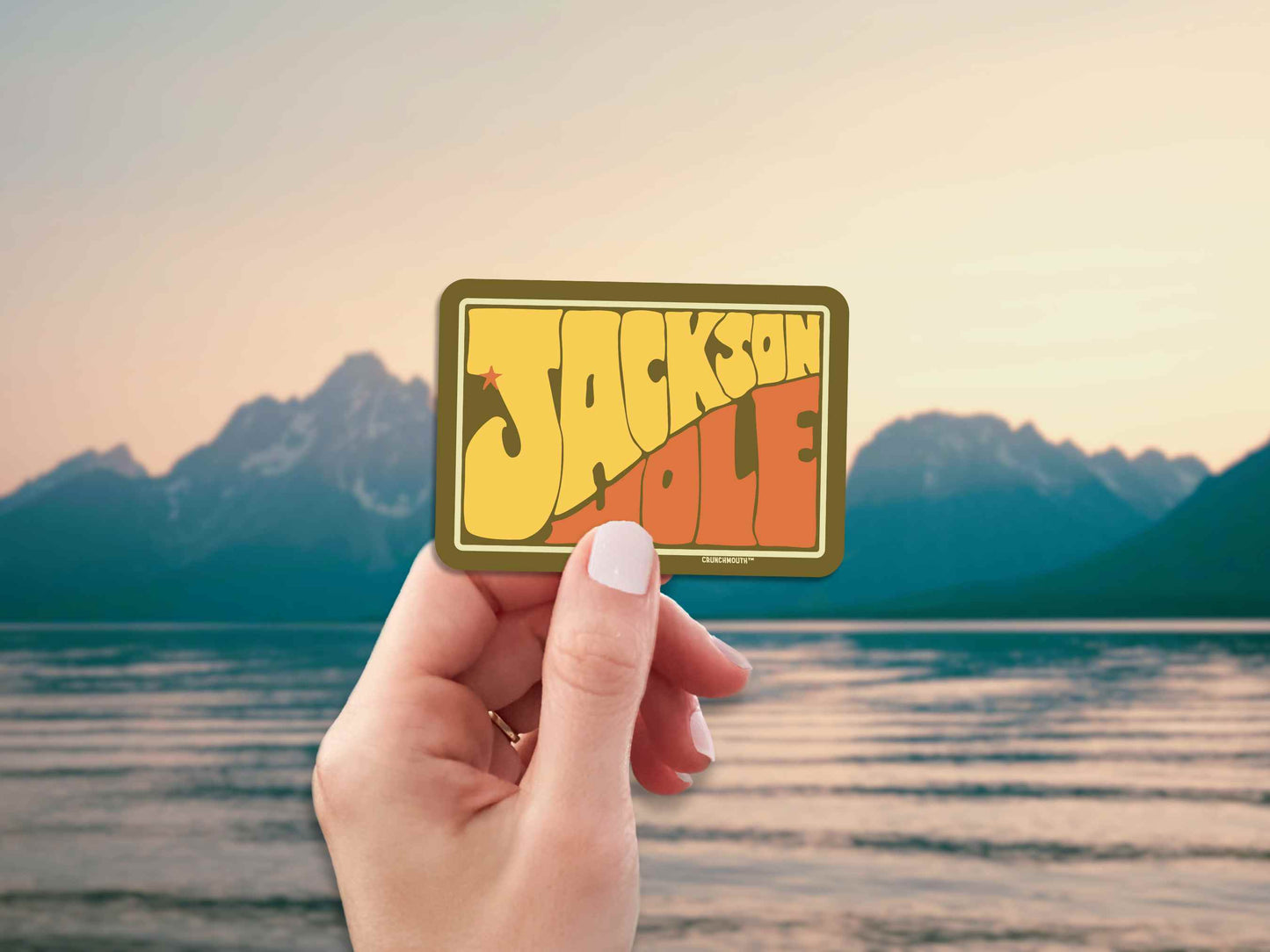 jackson hole travel luggage sticker, hand display, mountains lake background