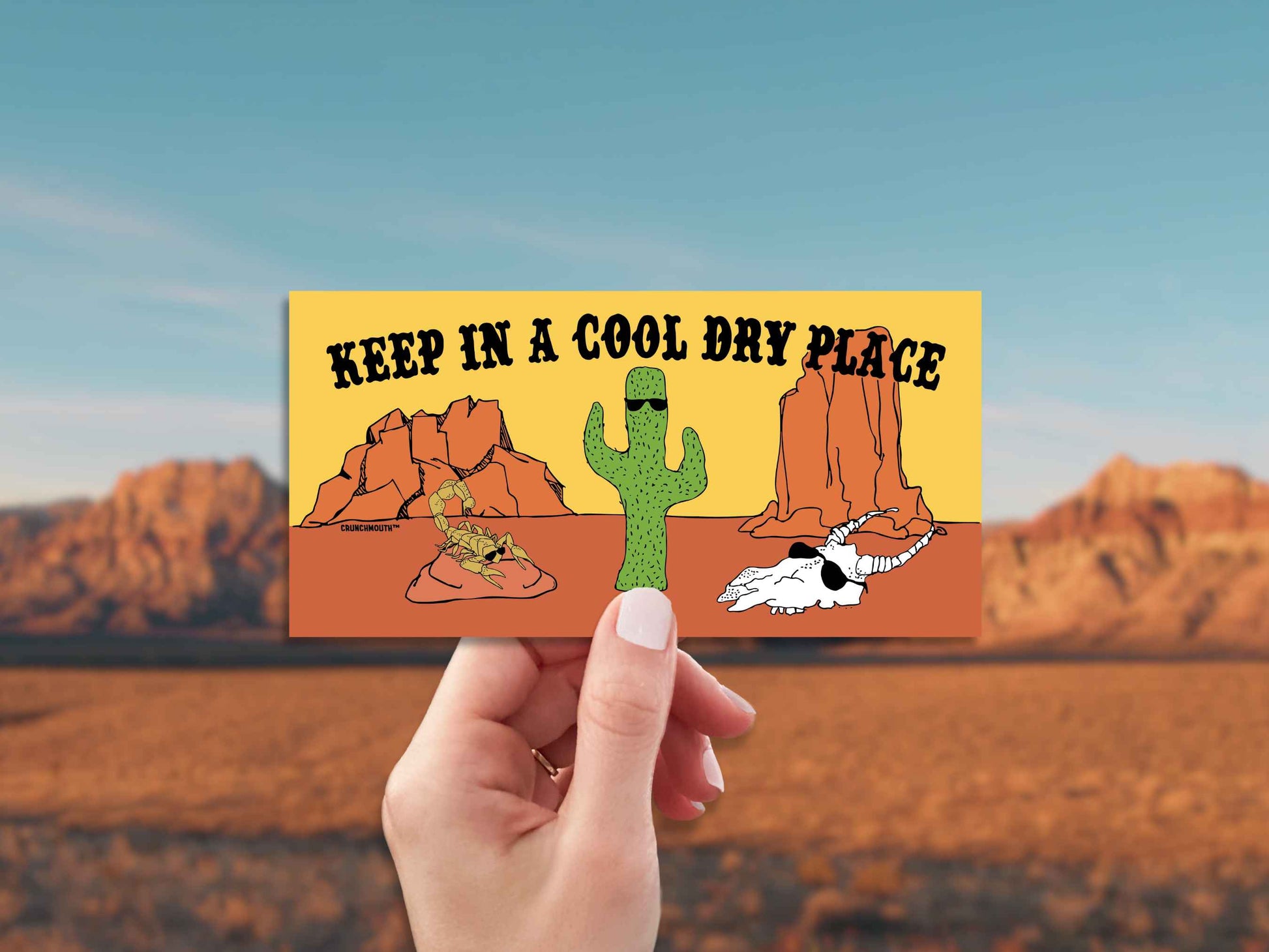keep in a cool dry place bumper sticker, hand display, red rocks desert background