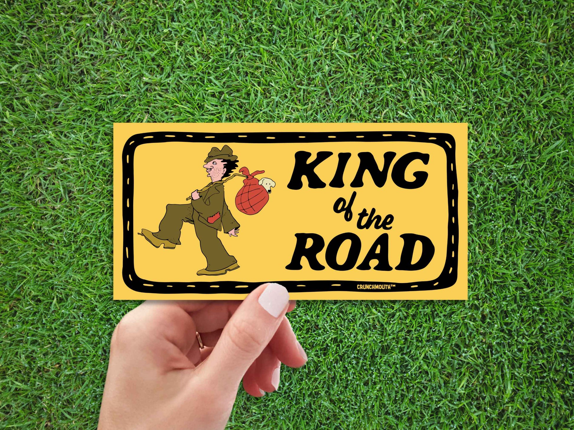 king of the road bumper sticker, hand display, green grass background