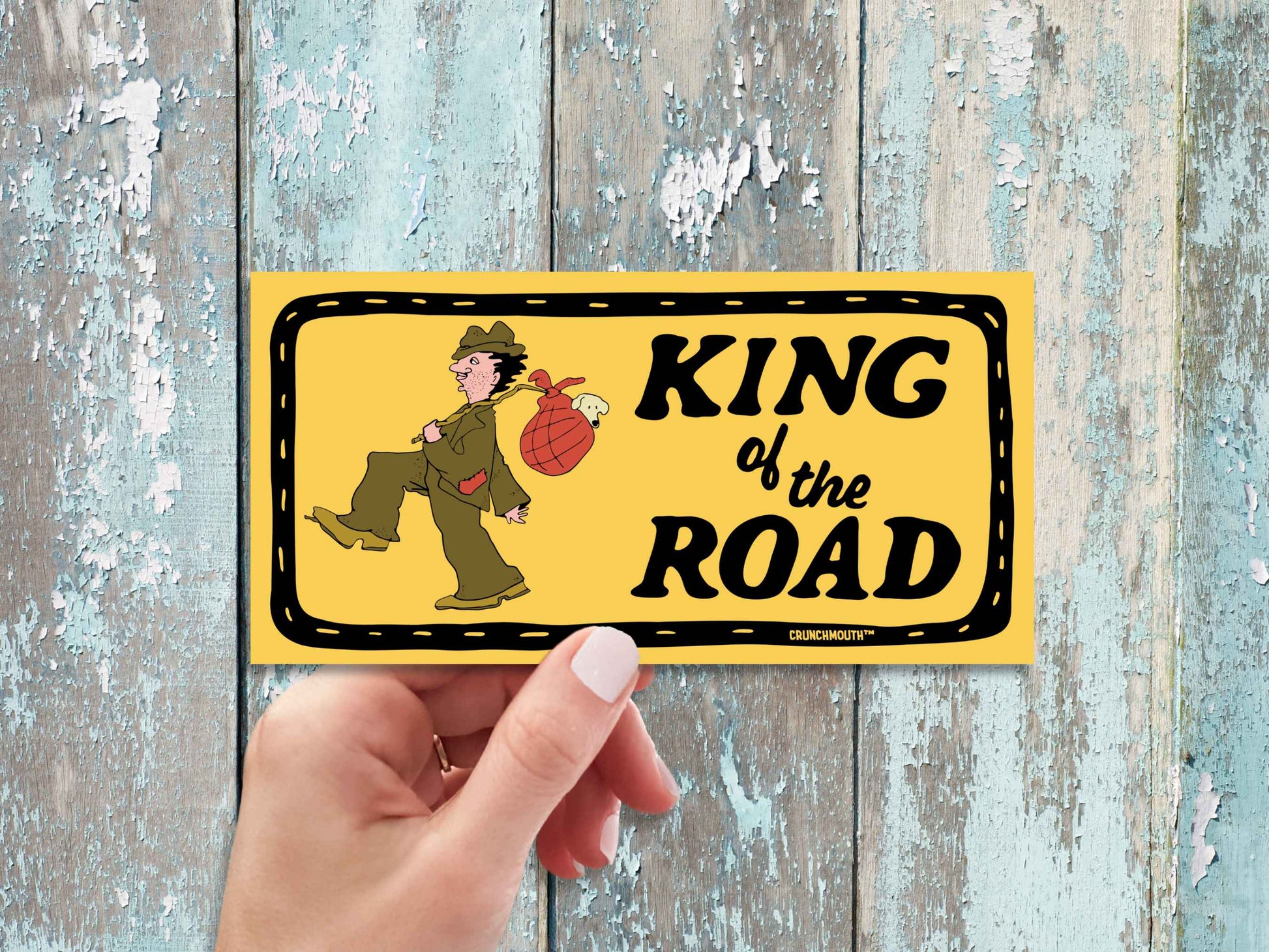 king of the road bumper sticker, hand display, wood panel background