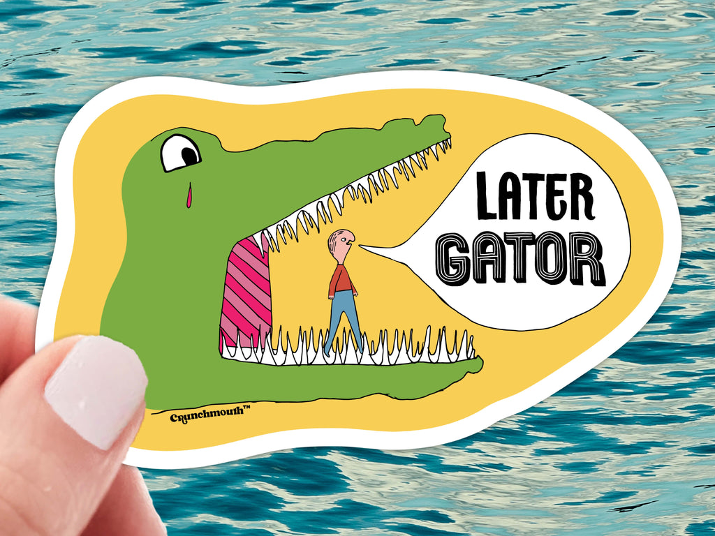 later gator funny laptop sticker,held in hand, blue ocean water background