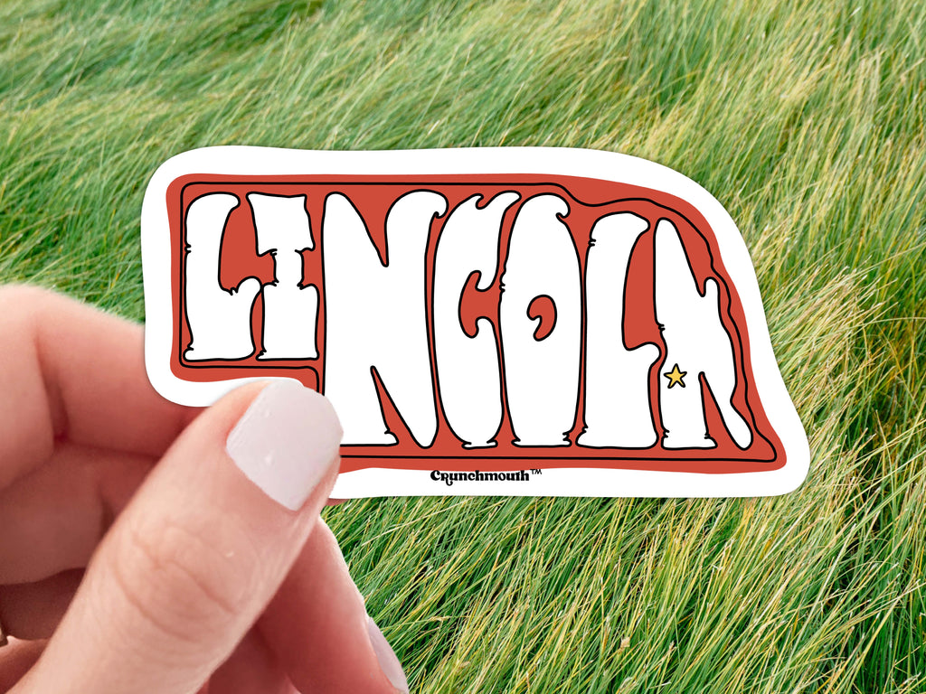 lincoln nebraska laptop sticker, held in hand, green grass background