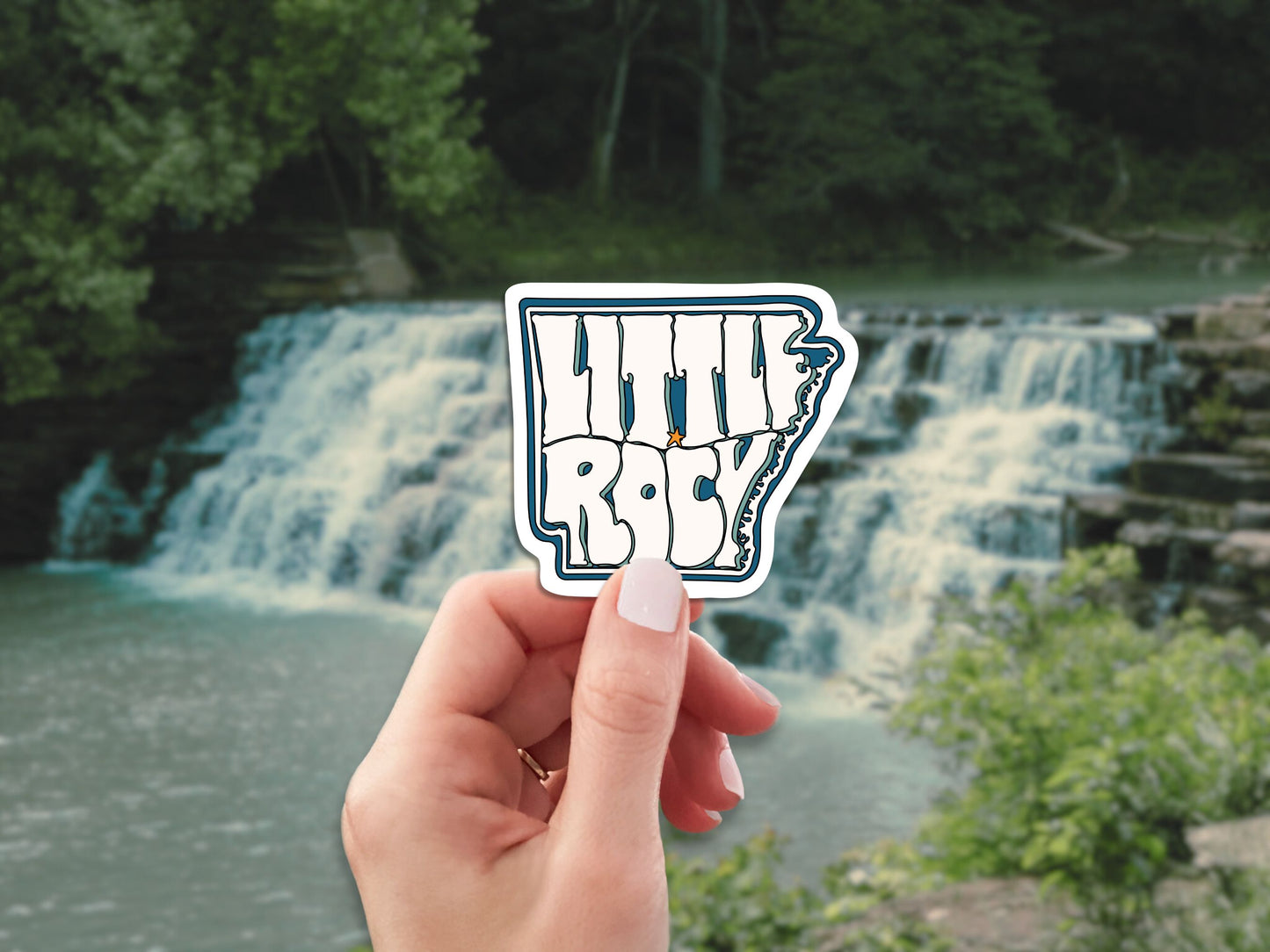 little rock travel luggage sticker, hand display, waterfall background