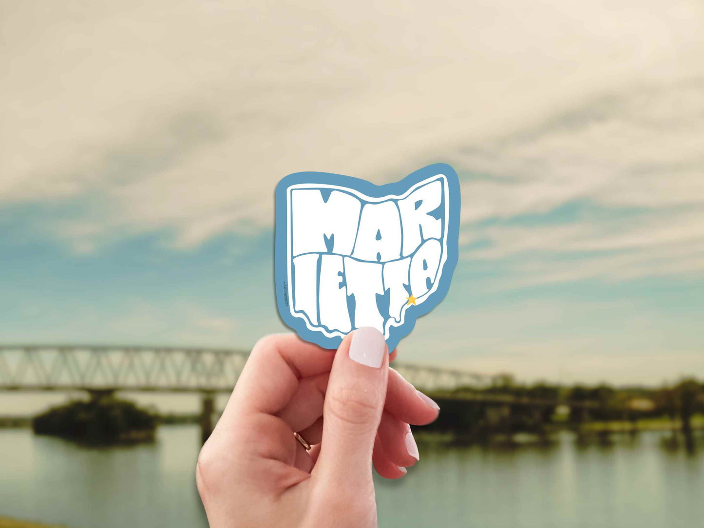marietta ohio travel luggage sticker, hand display, bridge over river landscape background