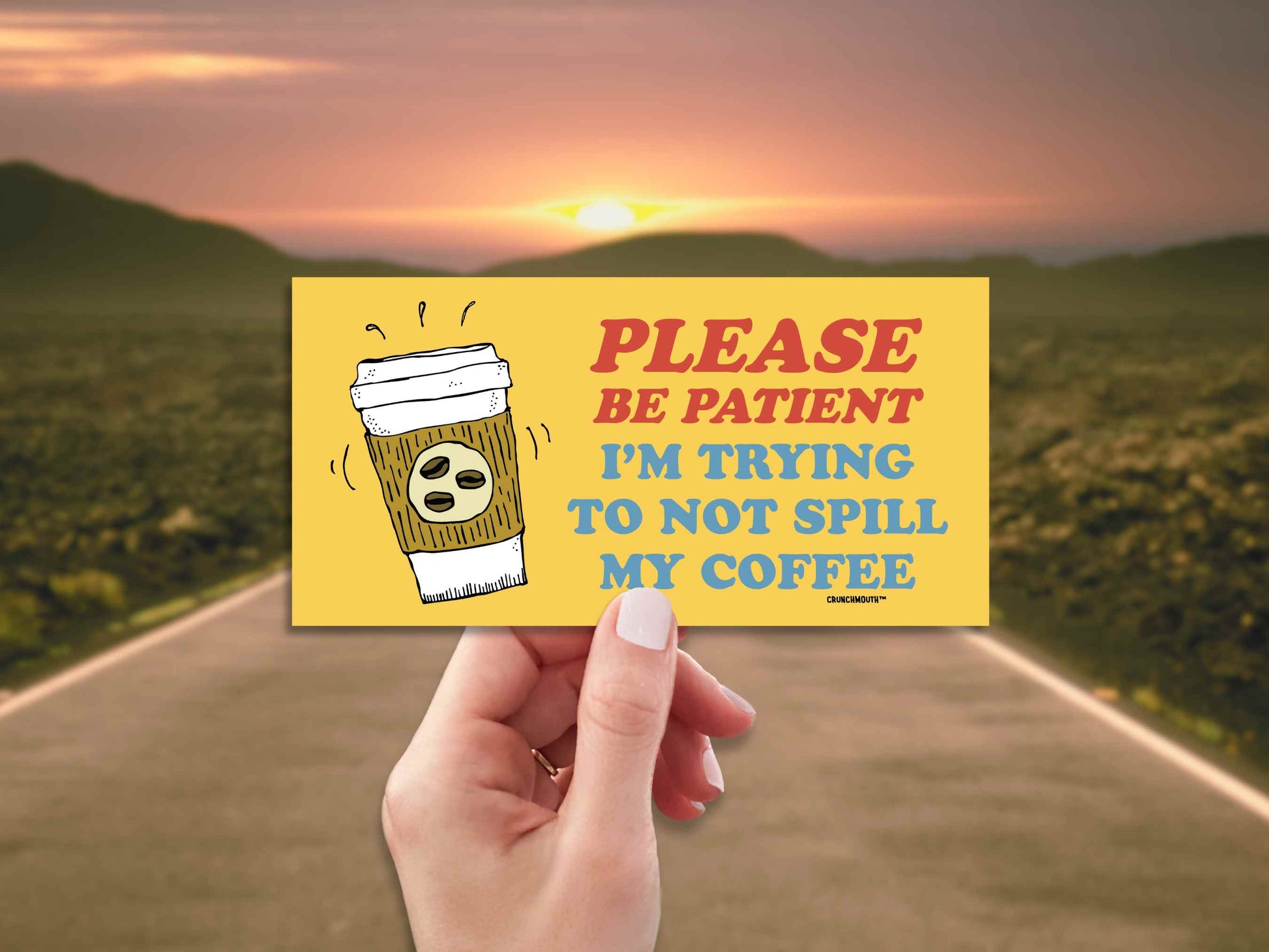please be patient I'm trying to not spill my coffee, funny bumper sticker, hand display, open road background