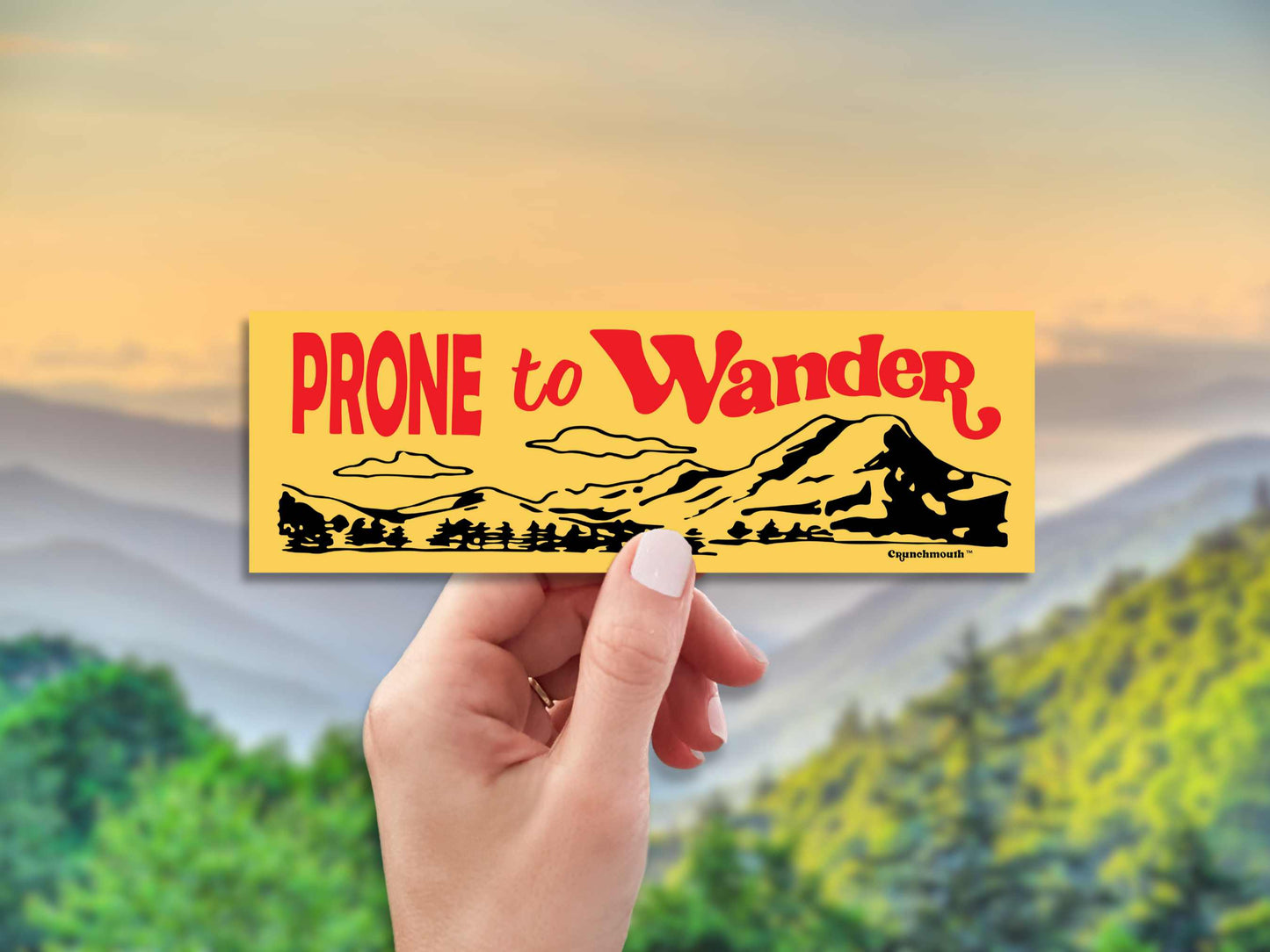 prone to wander bumper sticker, yellow, hand display, mountain range landscape background