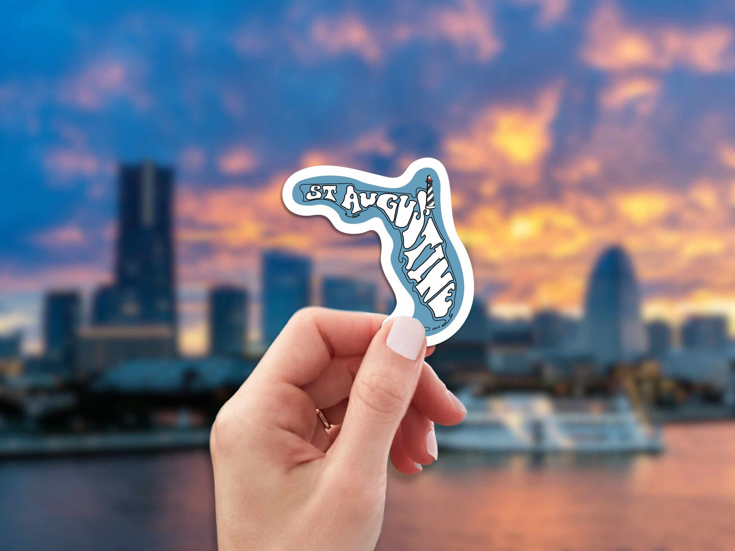 st augustine travel luggage sticker, hand display, blurred skyline landscape background