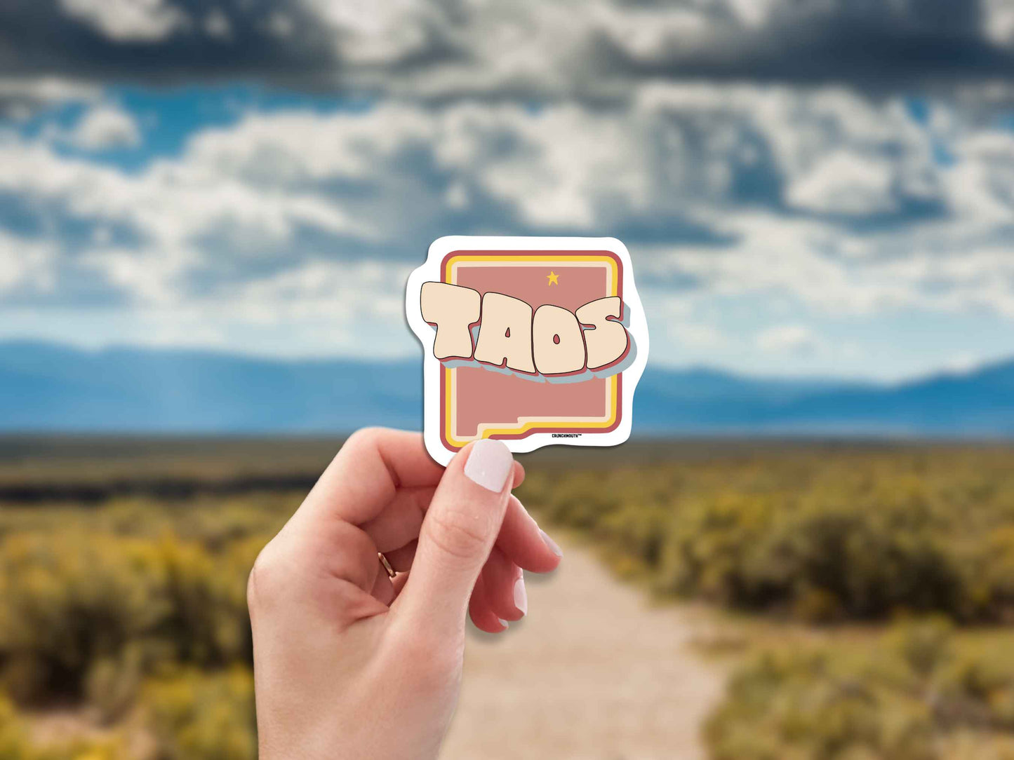 taos travel luggage sticker, hand display, blurred landscape background