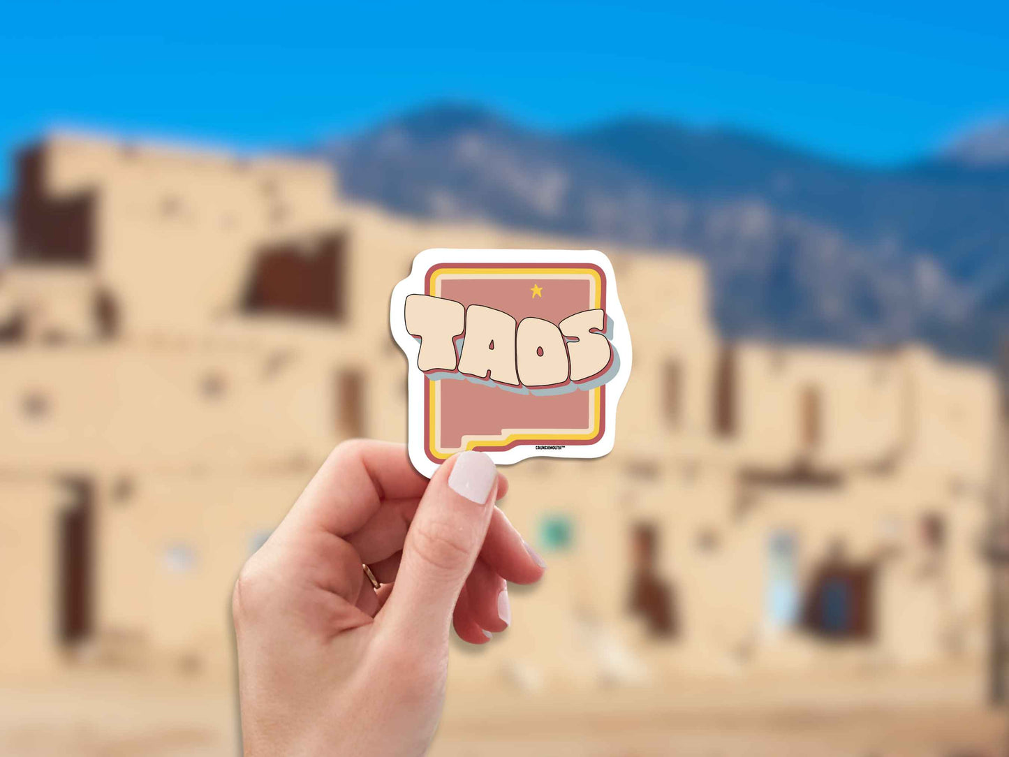 taos travel luggage sticker, hand display, blurred landscape background