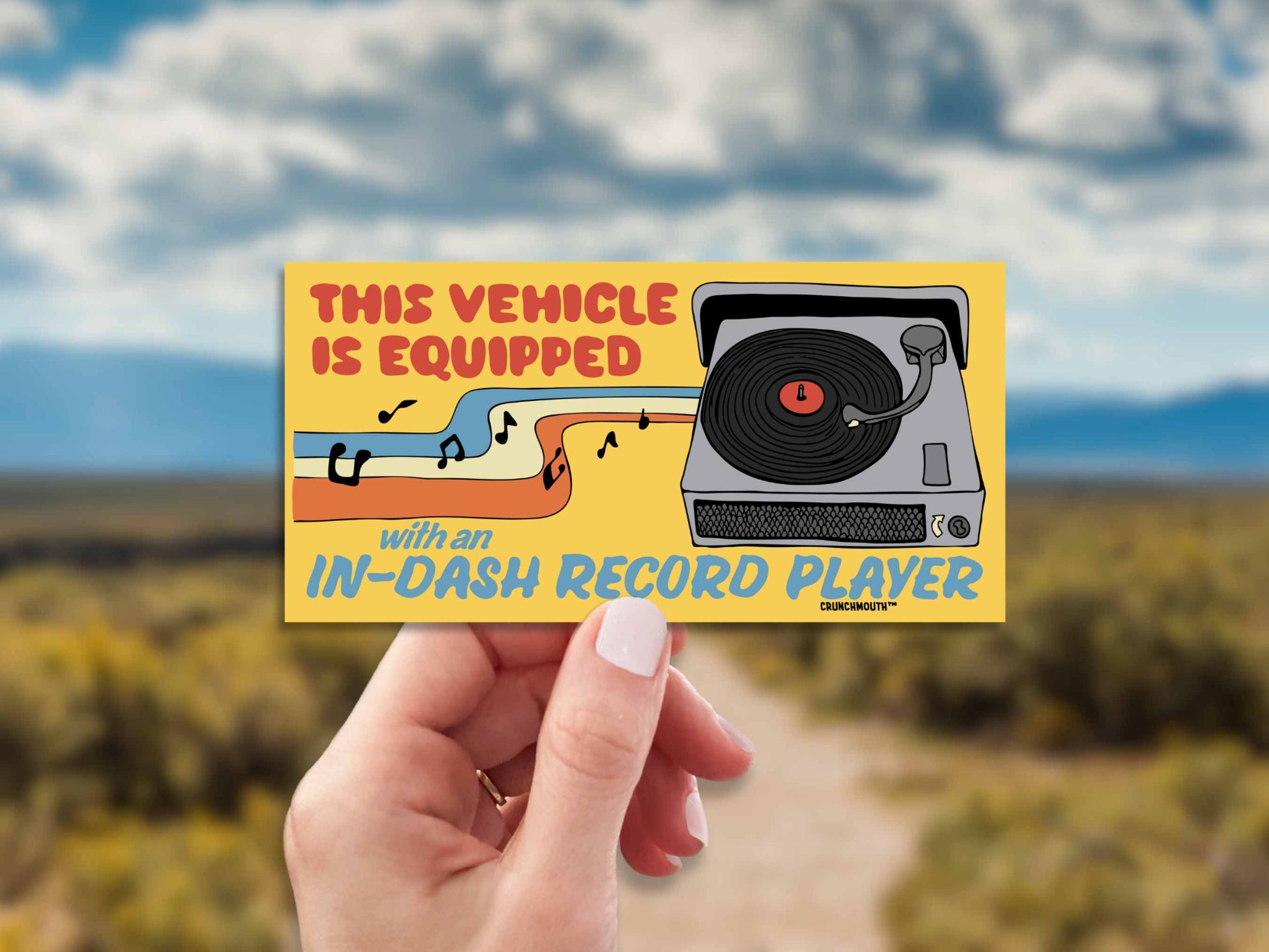 audiophile bumper sticker, hand display, open road background