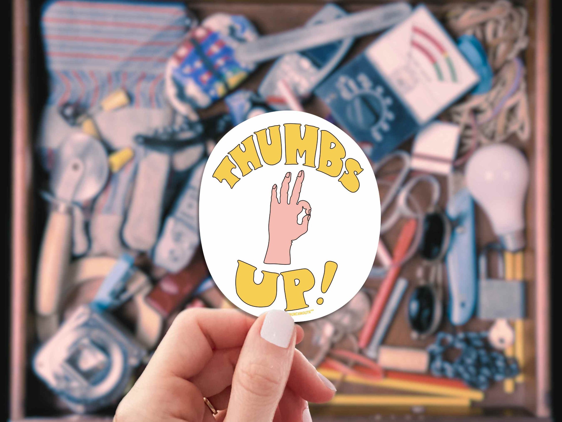 thumbs up sarcastic motivational sticker, hand display, junk drawer background