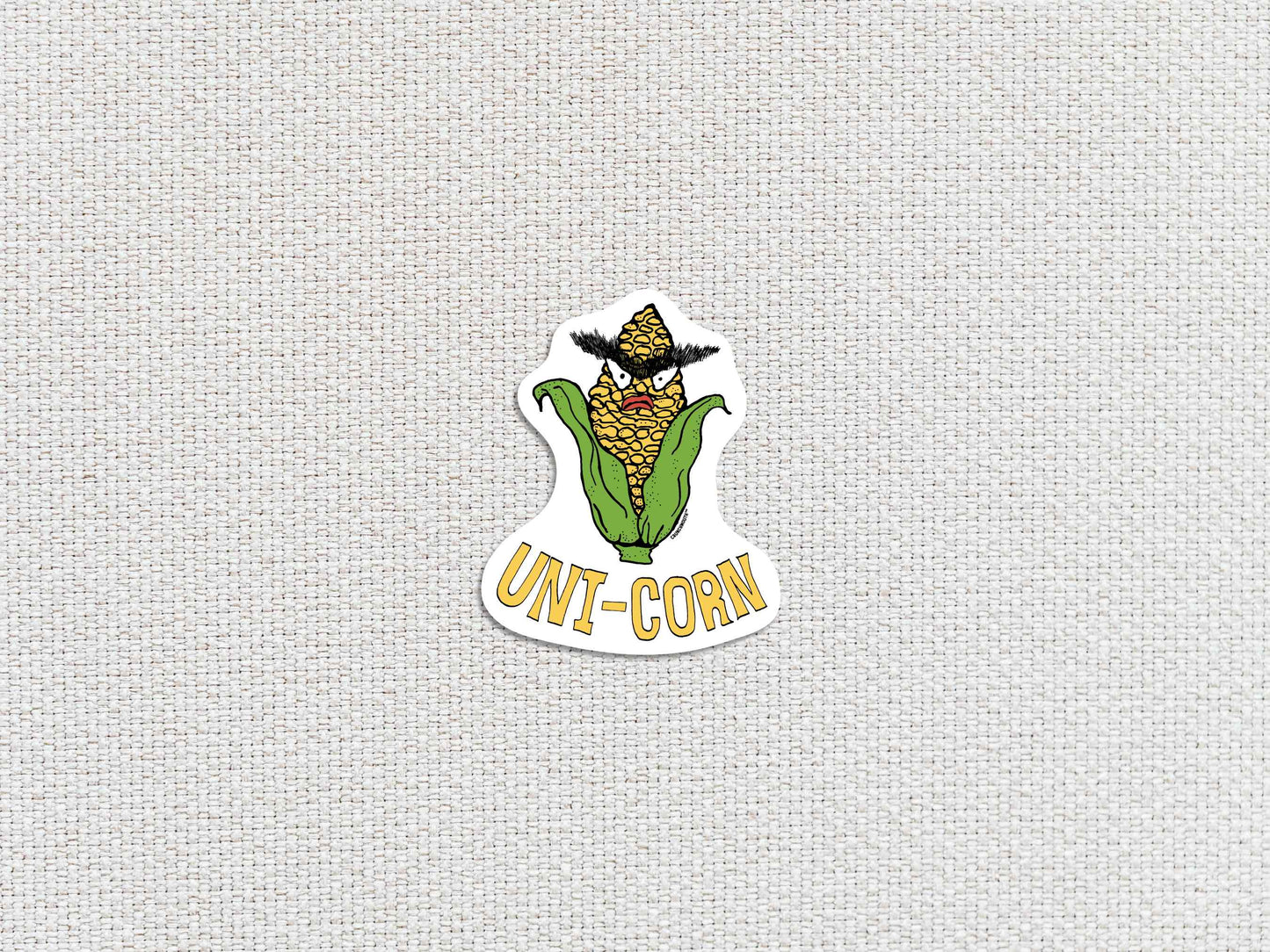 uni-corn laptop sticker, ear of corn with unibrow, white textured background