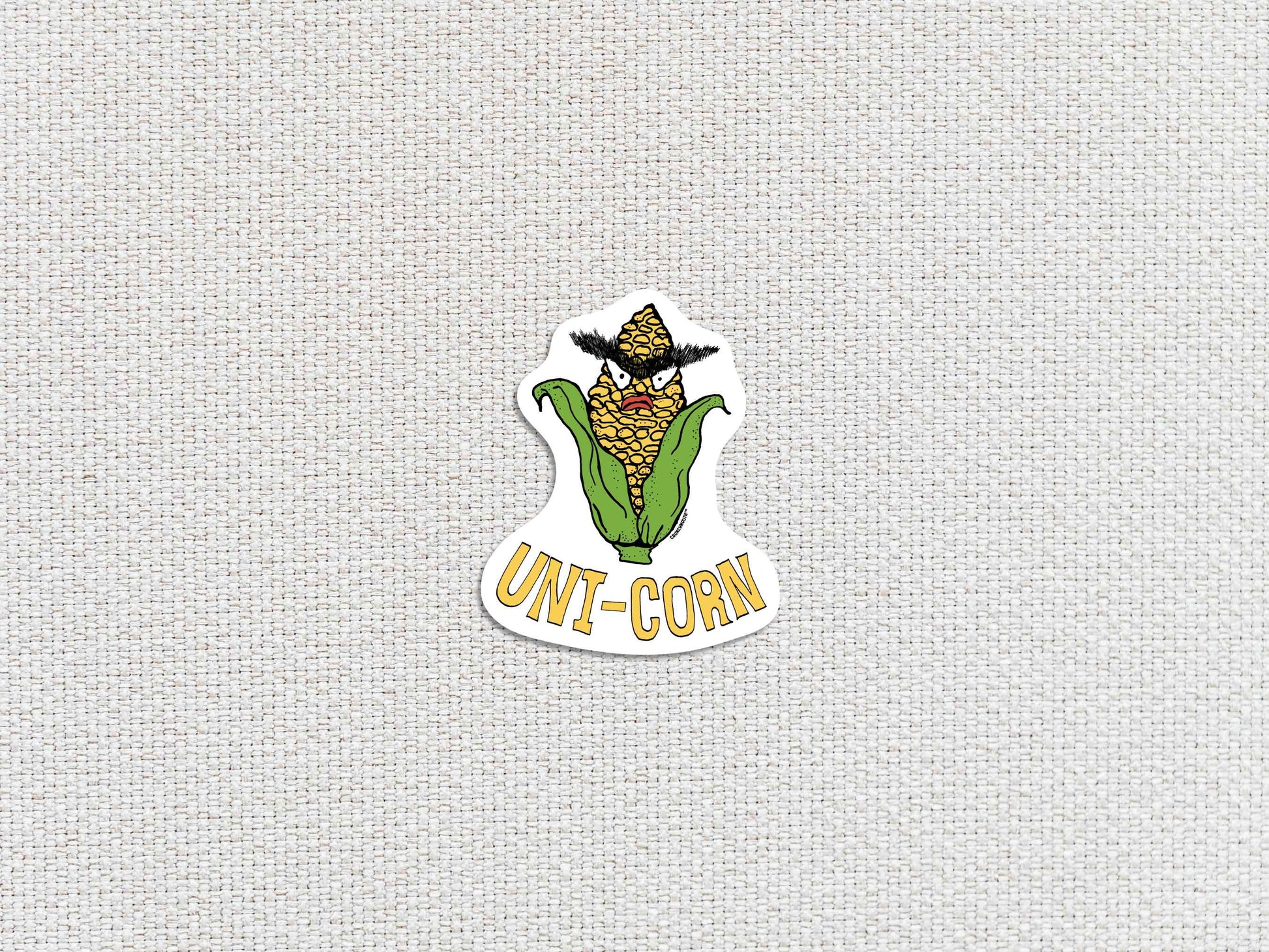 uni-corn laptop sticker, ear of corn with unibrow, white textured background