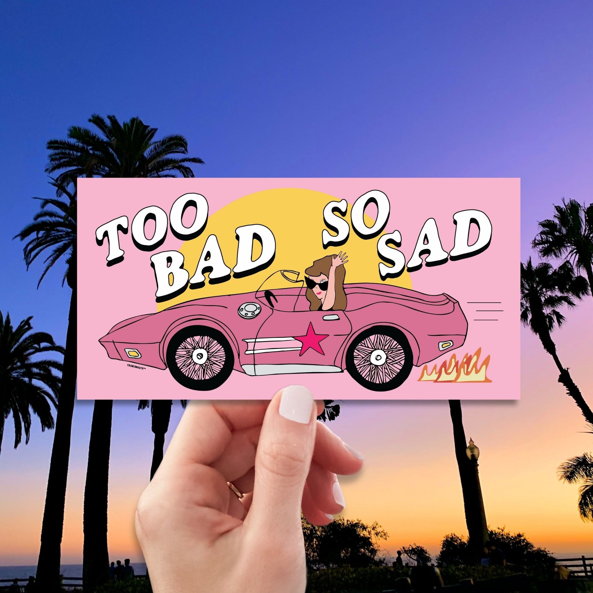 too bad so sad bumper sticker, hand display, malibu palm trees background