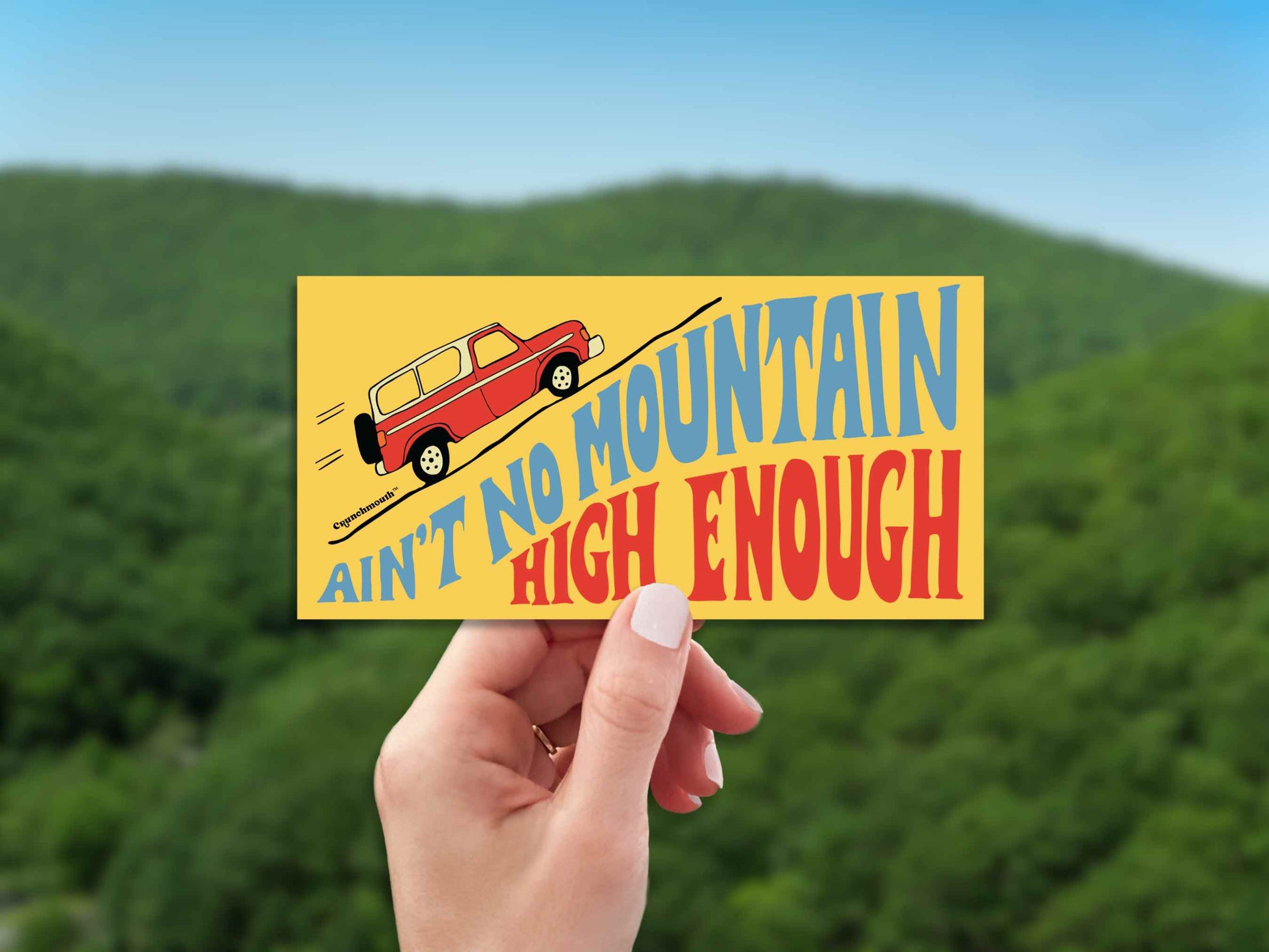 aint no mountain high enough bumper sticker, hand display, green mountains background