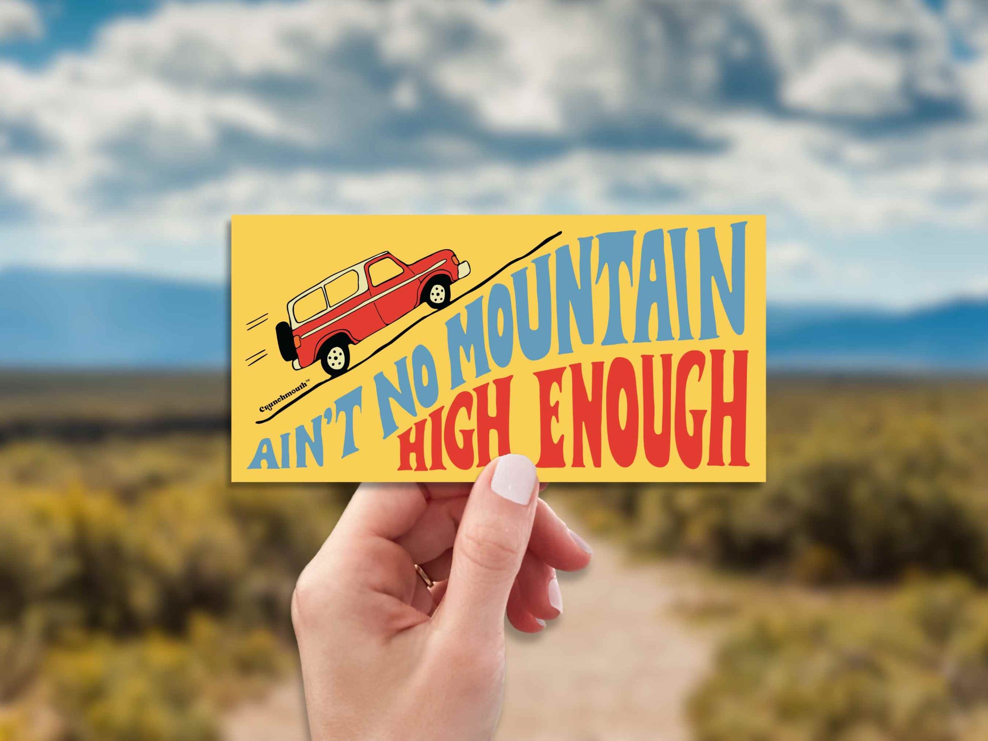 aint no mountain high enough bumper sticker, hand display, dirt road background