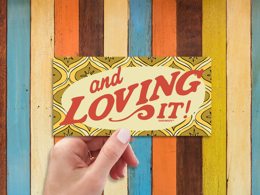 and loving it bumper sticker, hand display, multi-color wood panel background