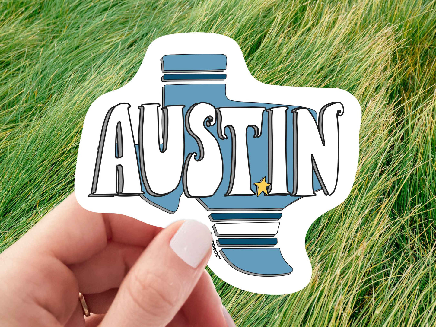 austin sticker, hand display, green grass background