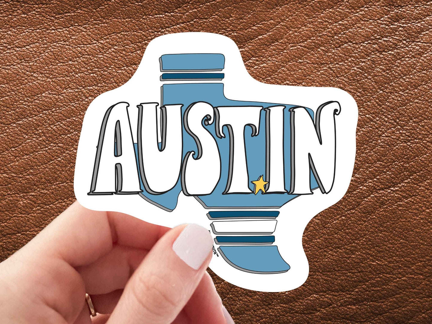 austin sticker, hand display, brown leather background