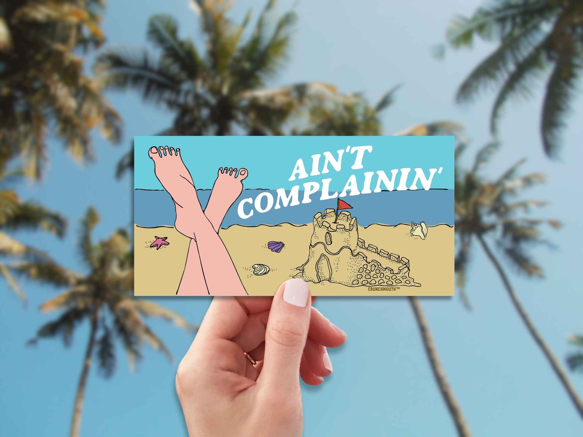 beach vibes bumper sticker, ain't complainin', hand display, palm trees background