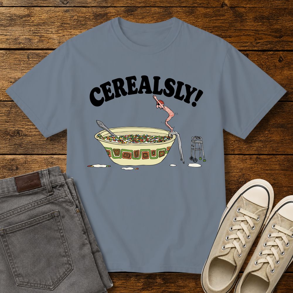 blue jean graphic T-shirt mockup featuring the phrase “Cerealsly!” above a humorous illustration of an elderly person diving into a giant bowl of cereal, styled with gray jeans and beige sneakers on a rustic wood background.