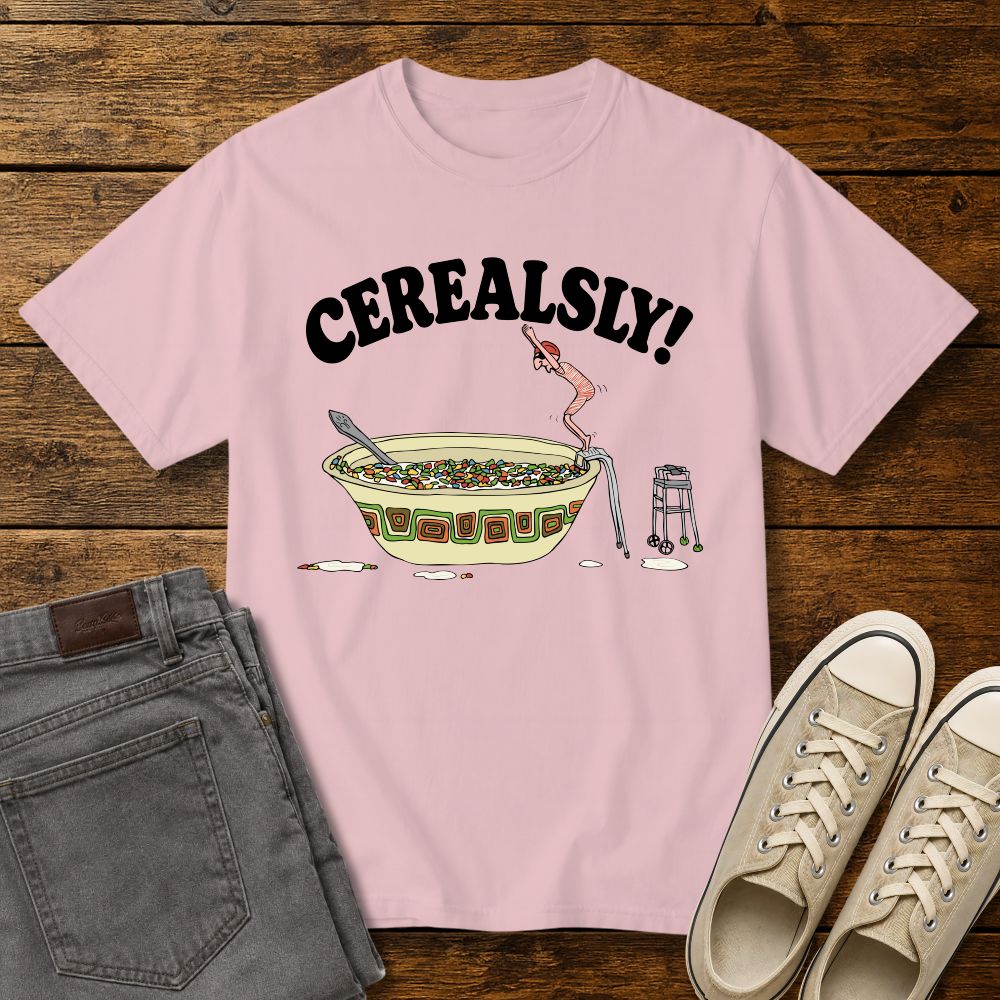 blossom pink graphic T-shirt mockup featuring the phrase “Cerealsly!” above a humorous illustration of an elderly person diving into a giant bowl of cereal, styled with gray jeans and beige sneakers on a rustic wood background.