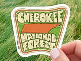 cherokee national forest sticker, held in hand, grass background