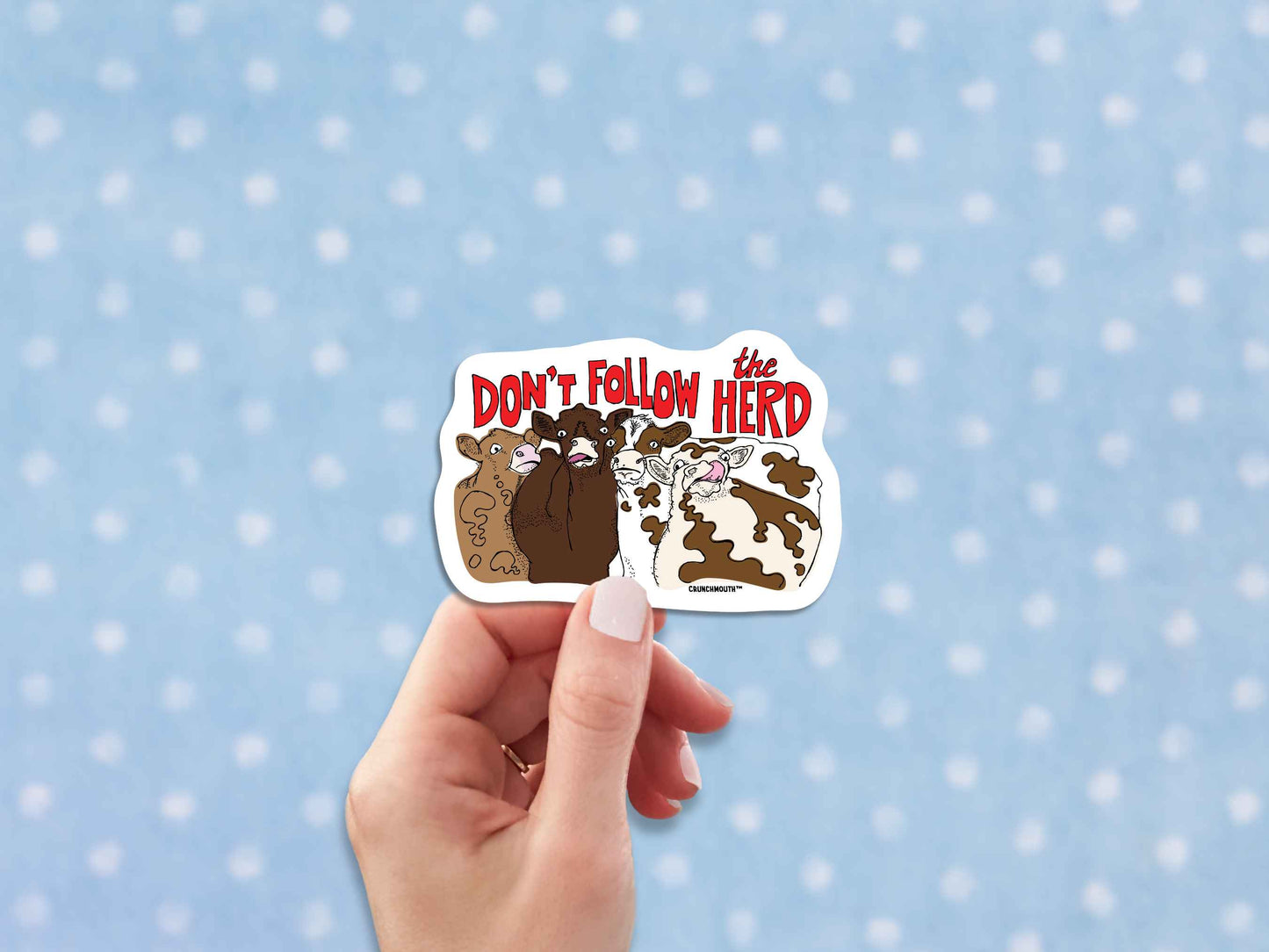 don't follow the herd sticker, hand display, polka dot fabric background