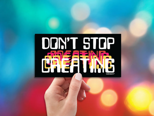 don't stop creating bumper sticker, hand display, colorful bright lights background