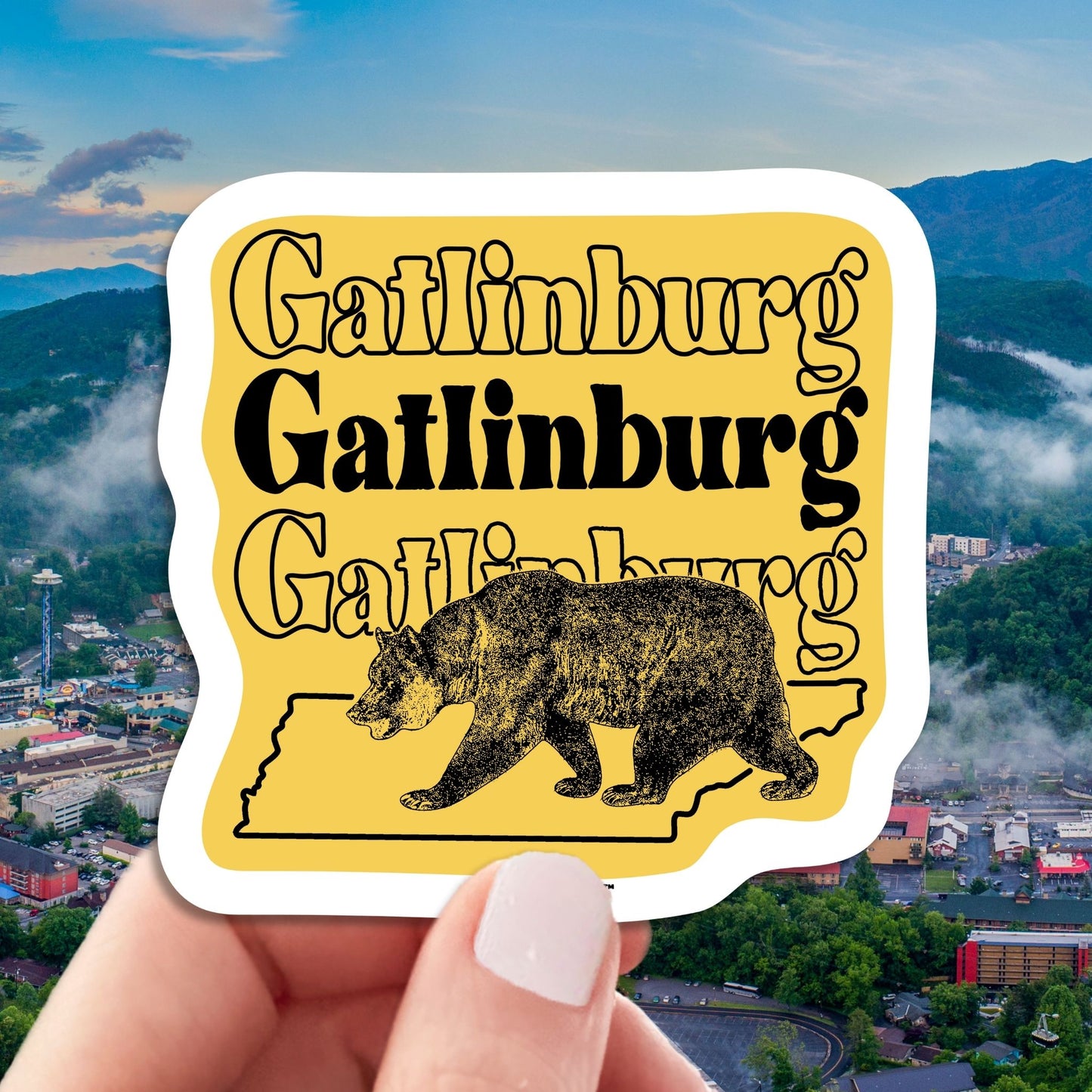 gatlinburg travel luggage sticker, hand display, aerial cityscape view background