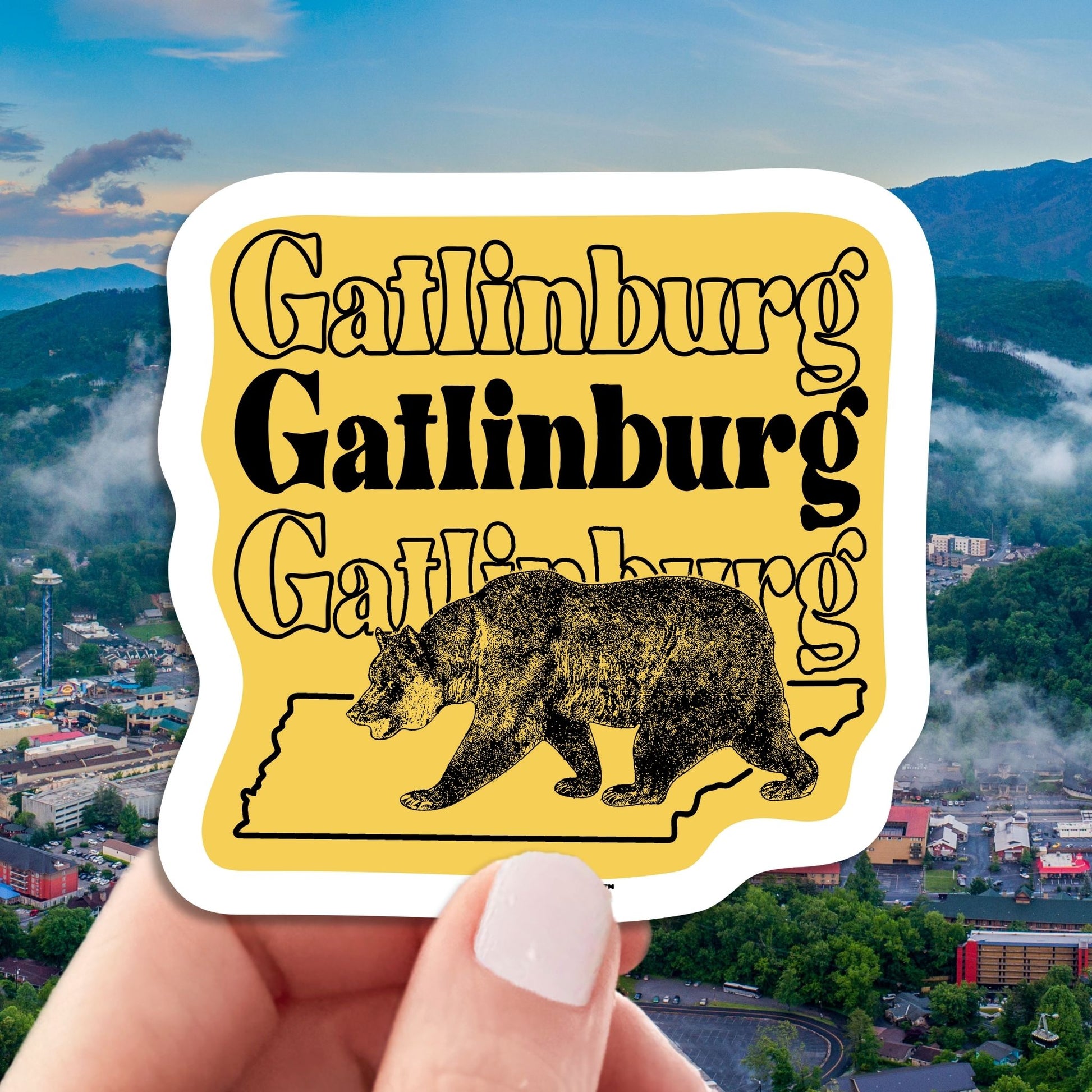 gatlinburg travel luggage sticker, hand display, aerial cityscape view background