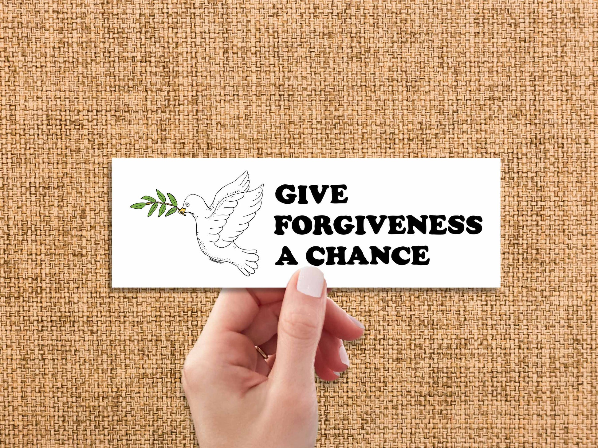give forgiveness a chance bumper sticker, hand display, brown textured fabric background
