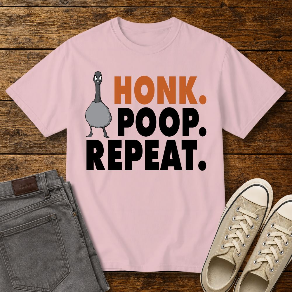 blossom pink graphic T-shirt mockup featuring a goose illustration and the phrase “Honk. Poop. Repeat.” in bold orange and black lettering, styled with gray jeans and beige sneakers on a rustic wood background.