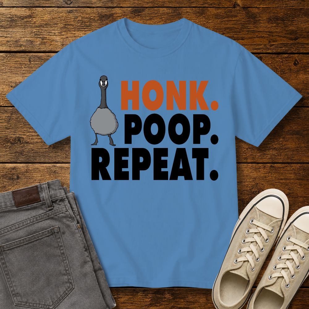 royal caribbean blue graphic T-shirt mockup featuring a goose illustration and the phrase “Honk. Poop. Repeat.” in bold orange and black lettering, styled with gray jeans and beige sneakers on a rustic wood background.