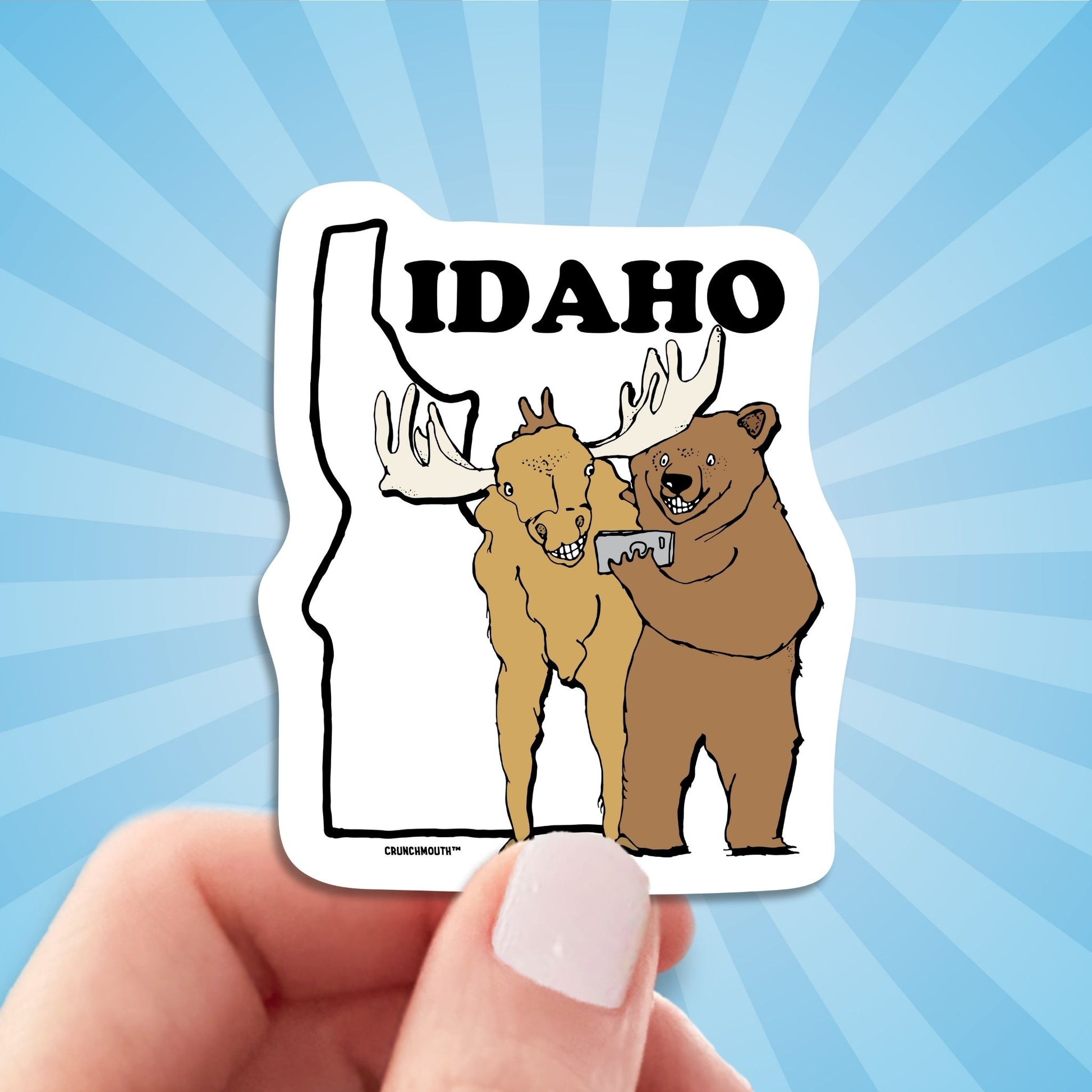 idaho travel luggage sticker, hand display, sun rays design background
