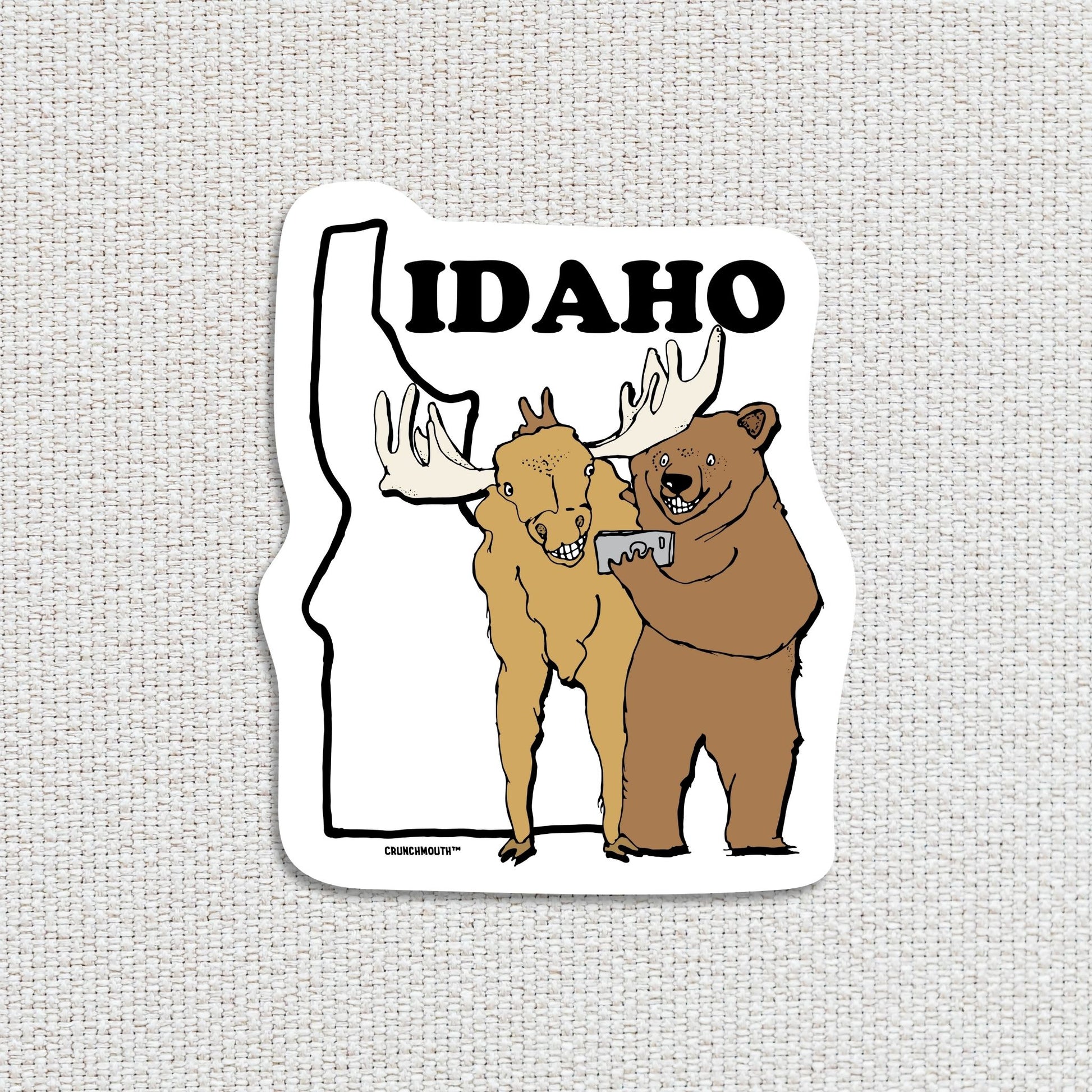 idaho travel luggage sticker, hand display, textured fabric background

