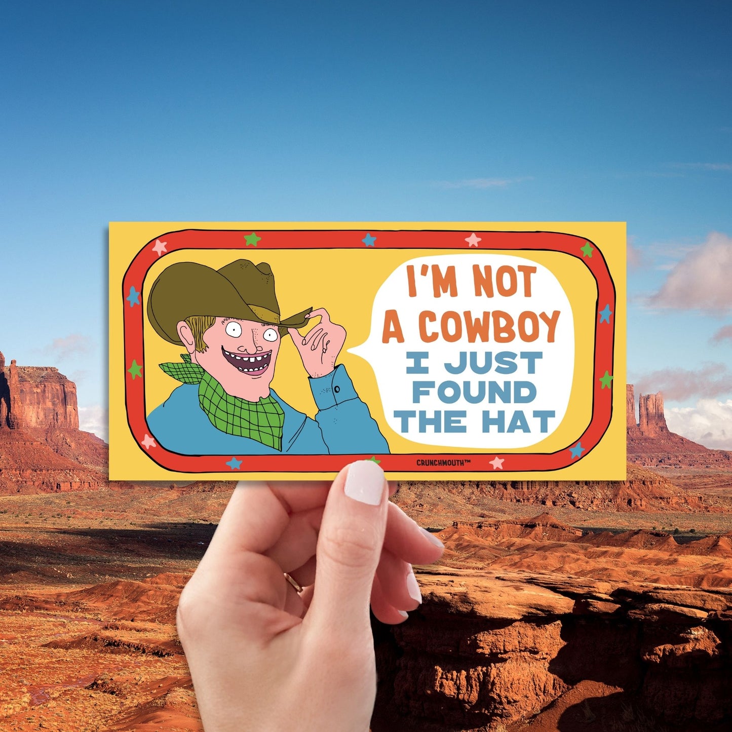 i'm not a cowboy (I just found the hat) funny western-themed bumper sticker, hand display, western landscape background