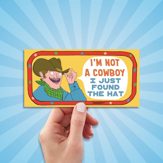 i'm not a cowboy (I just found the hat) funny western-themed bumper sticker, hand display, sun rays design background