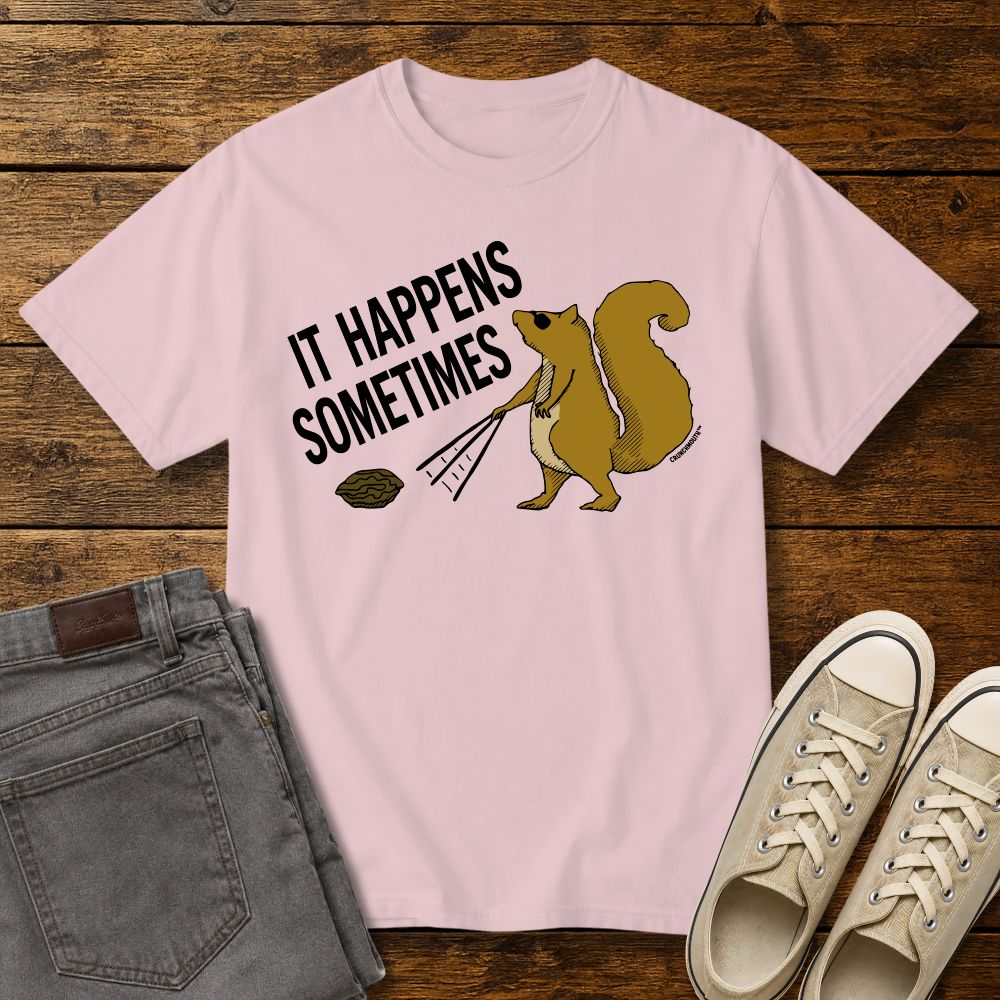 Funny squirrel graphic t-shirt on blossom color tee with ‘It Happens Sometimes’ text, shown in flat lay mockup with jeans and sneakers on rustic wood background