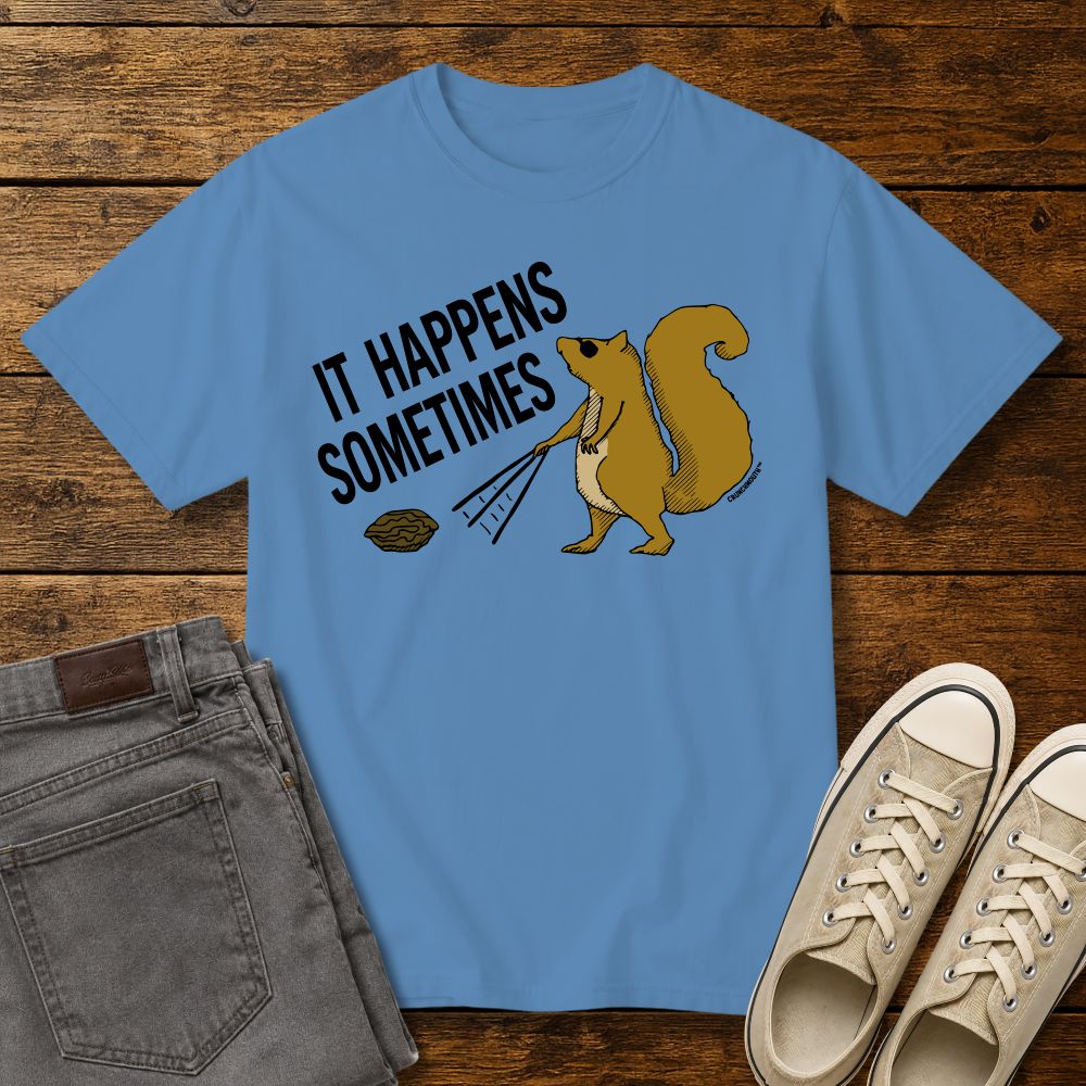 Funny squirrel graphic t-shirt on royal caribbean blue color tee with ‘It Happens Sometimes’ text, shown in flat lay mockup with jeans and sneakers on rustic wood background