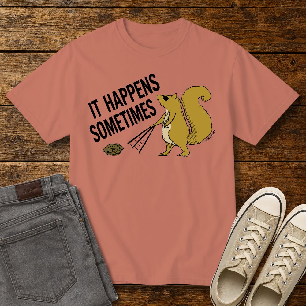Funny squirrel graphic t-shirt on terracotta color tee with ‘It Happens Sometimes’ text, shown in flat lay mockup with jeans and sneakers on rustic wood background